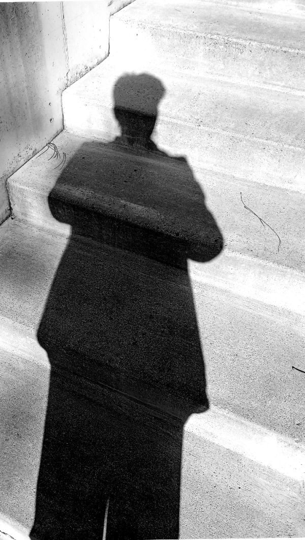 A shadow of a person at the base of some stairs.